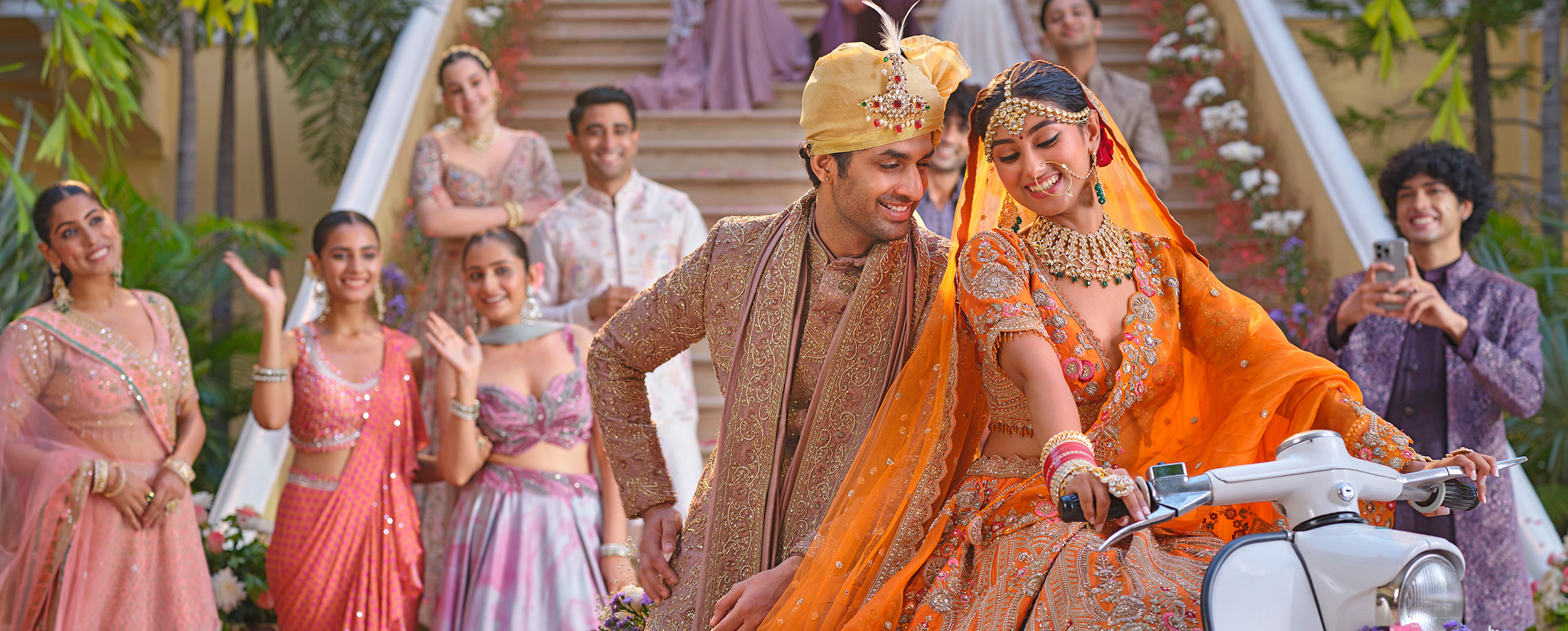 Bride wearing elegant orange lehenga, riding scooter with groom behind her Bride wearing elegant orange lehenga, riding scooter with groom behind her