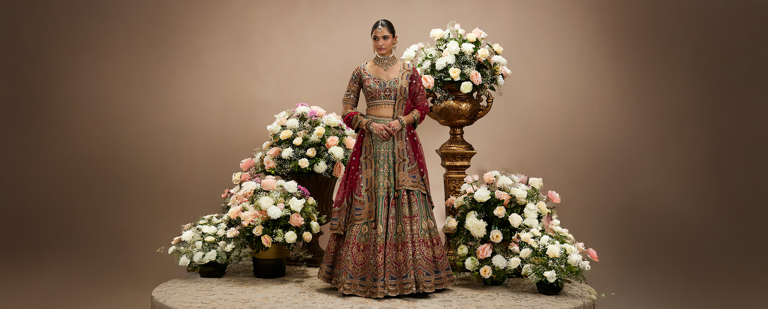 Woman modeling a heavy, intricately embroidered bridal lehenga, providing inspiration for a regal wedding outfit.
