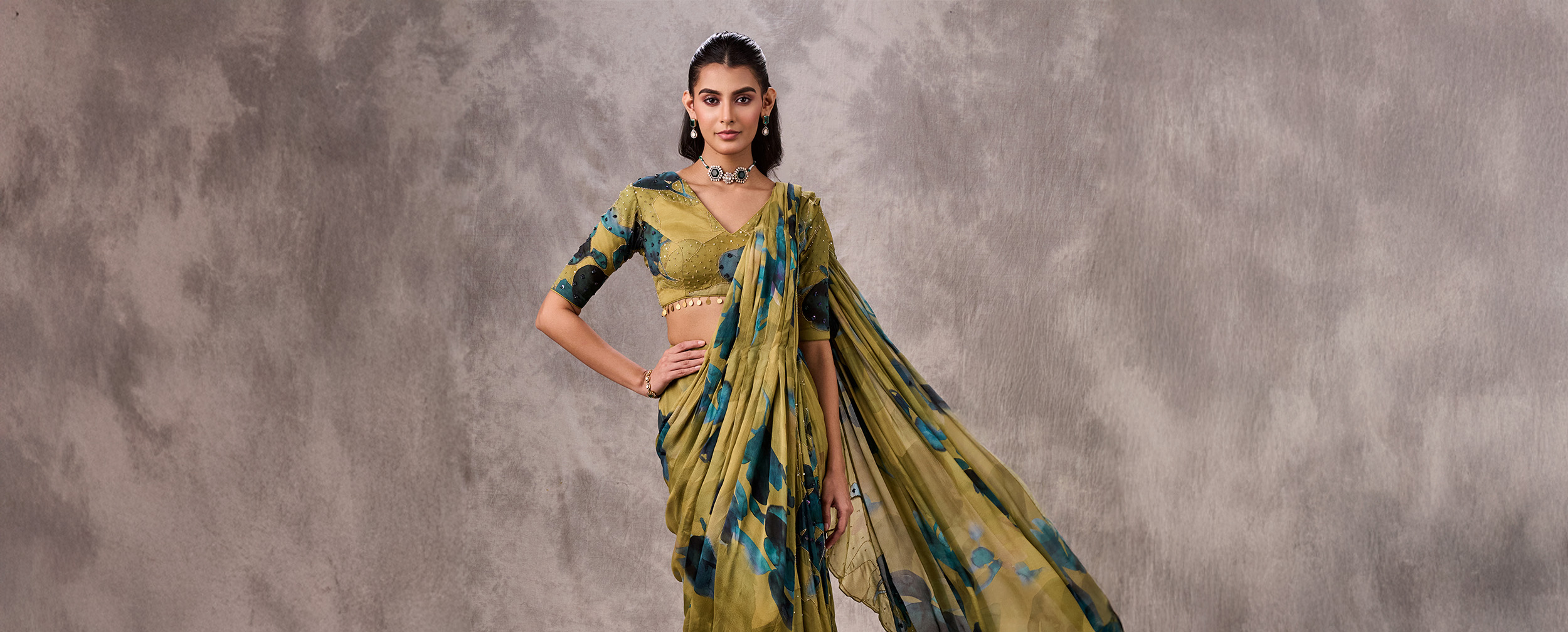 Woman styled in an olive green floral print saree with a matching embroidered blouse, showcasing a chic green saree color combination.