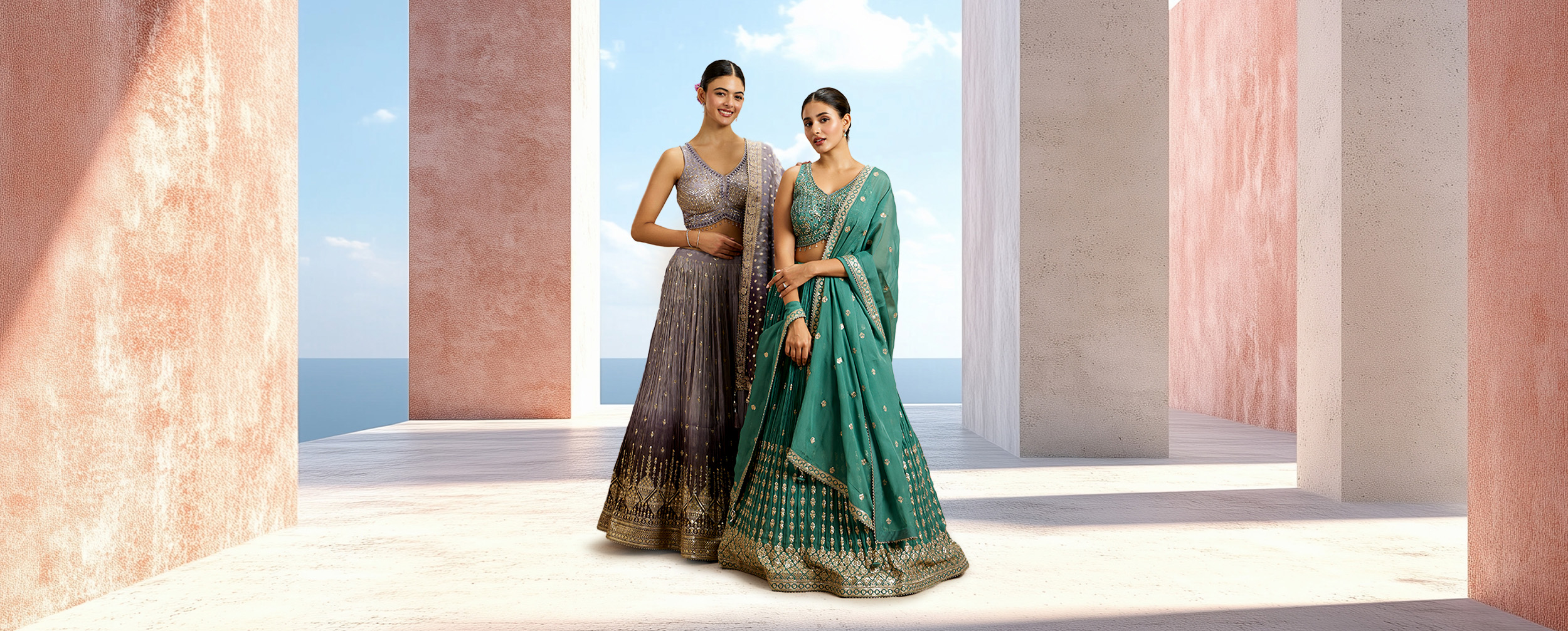 Two women modeling elegant grey and teal designer lehengas, providing outfit inspiration for a wedding guest.