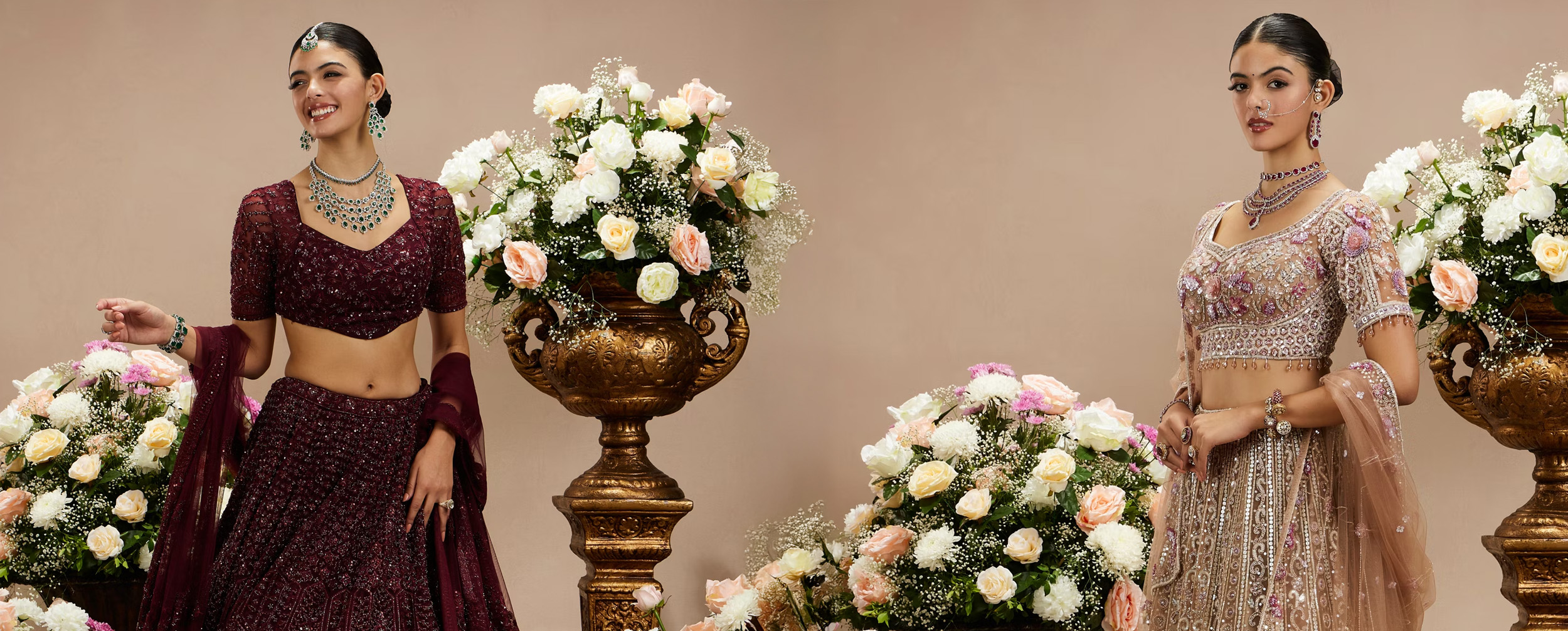 Two women modeling stunning maroon and gold embroidered designer lehengas, showcasing bridal styles every bride must know.