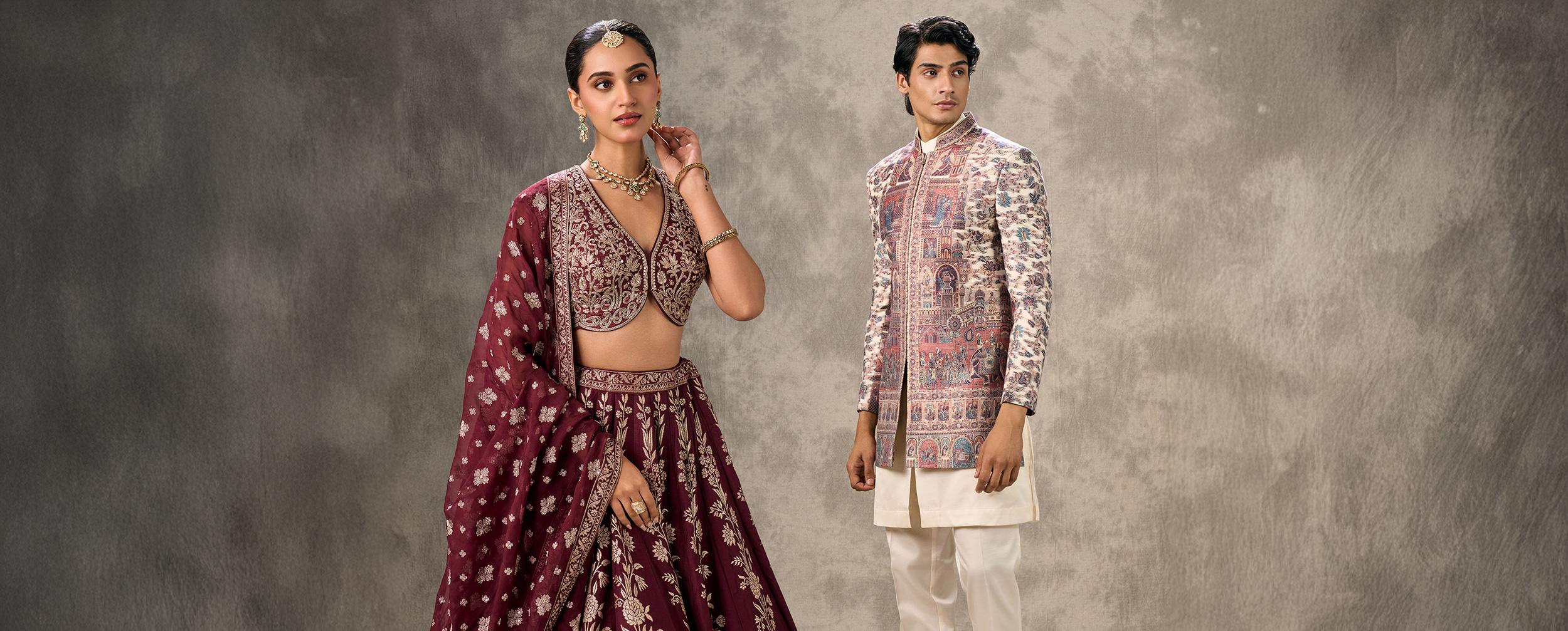Stylish couple in traditional Navratri outfits — woman in a maroon embroidered lehenga choli with dupatta, and man in a cream churidar with a printed sherwani jacket — perfect for Garba and Dandiya celebrations. Stylish couple in traditional Navratri outfits — woman in a maroon embroidered lehenga choli with dupatta, and man in a cream churidar with a printed sherwani jacket — perfect for Garba and Dandiya celebrations.